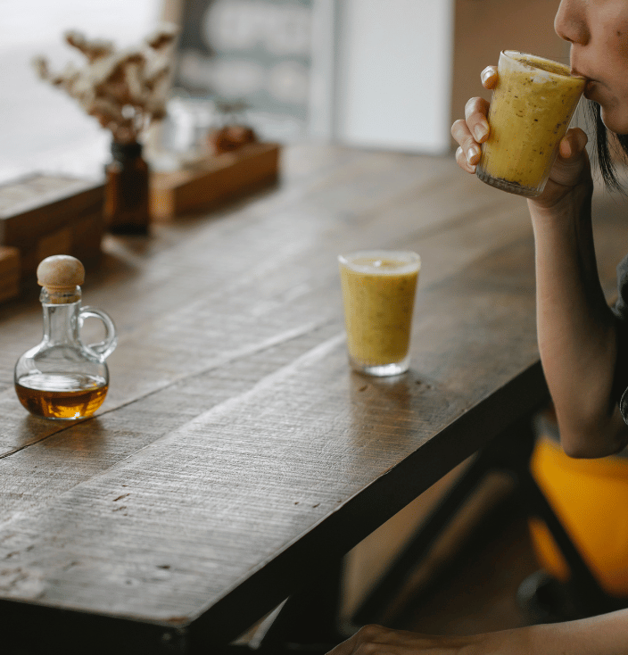 Person sitting at a table drinking a beverage