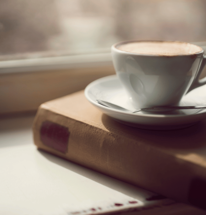 A cup of coffee sitting on a closed book