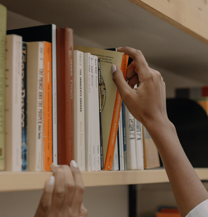 Person's hand pulling a book off of a book shelf